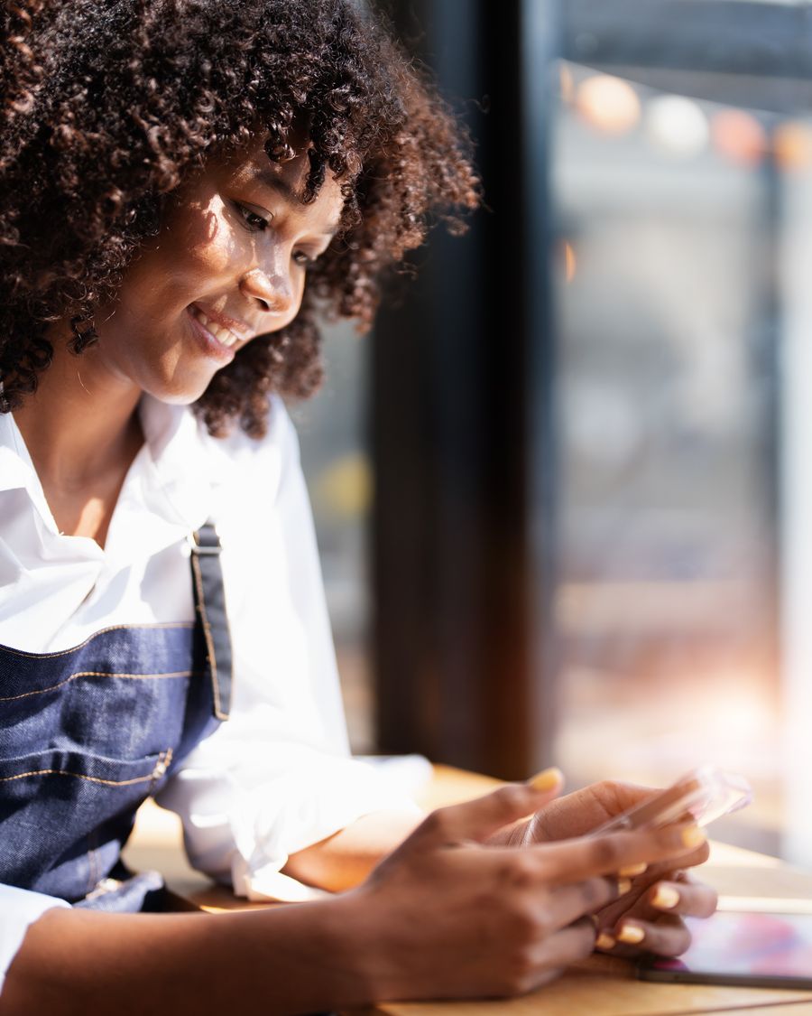 Empreendedora atendendo um cliente pelo WhatsApp no celular